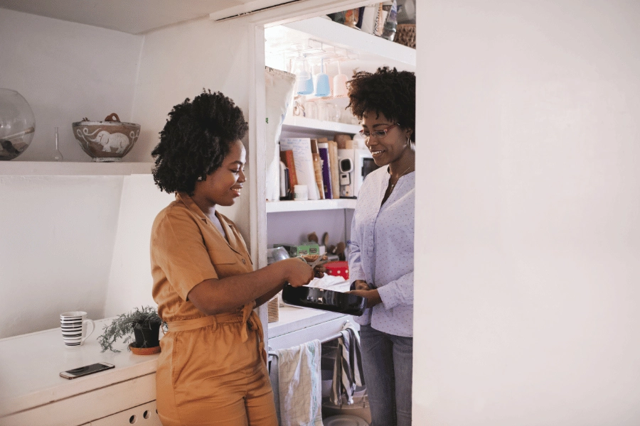 two girl roommates cooking and hanging out together in the kitchen